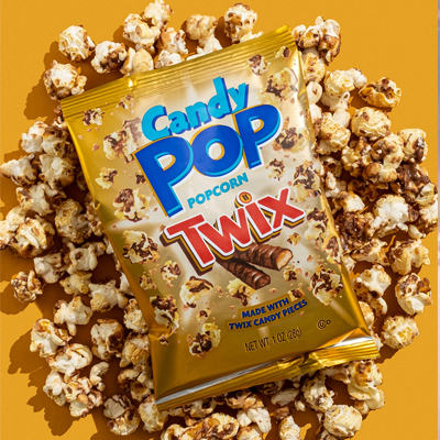 Bag of Candy Pop Popcorn Twix surrounded by chocolate and caramel-coated popcorn pieces