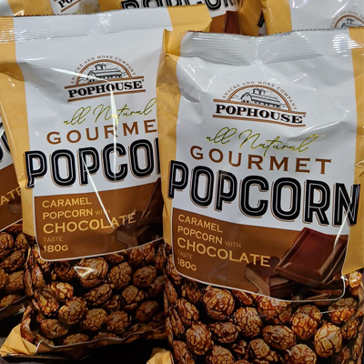 Bags of PopHouse Gourmet Popcorn featuring caramel popcorn with a rich chocolate taste.