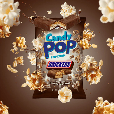 Bag of Candy Pop Popcorn Snickers surrounded by caramel-drizzled popcorn and peanuts.
